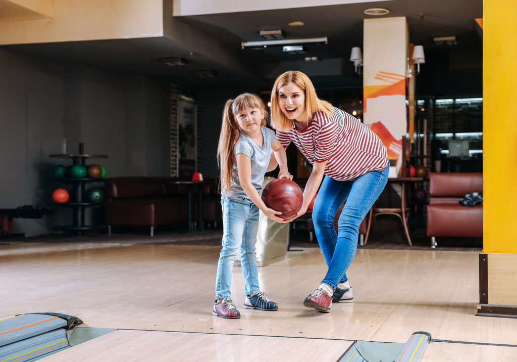 Mother and children bowling together as a family