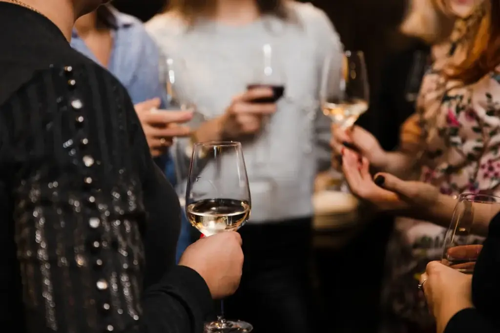 Close-up of people's hands holding wine glasses at a social gathering.