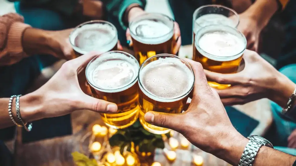 Six hands clink full beer glasses together in a toast, viewed from above.