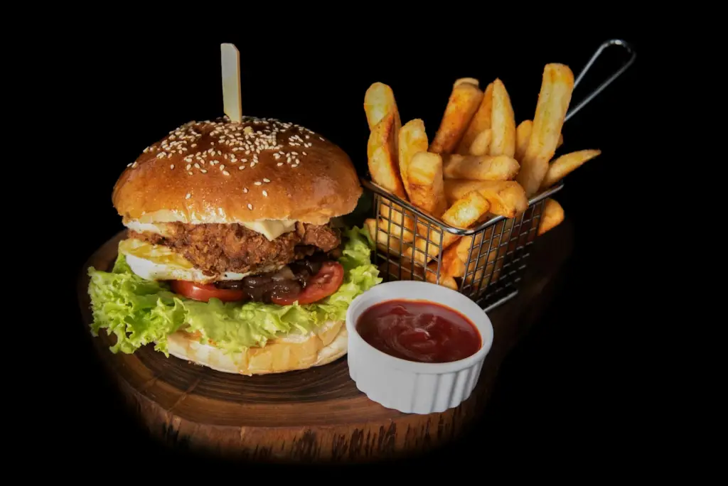 Juicy burger with crispy fries and dipping sauce in a basket