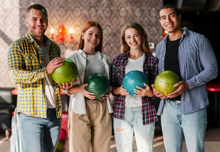 Group of friends smiling and holding colorful bowling balls together