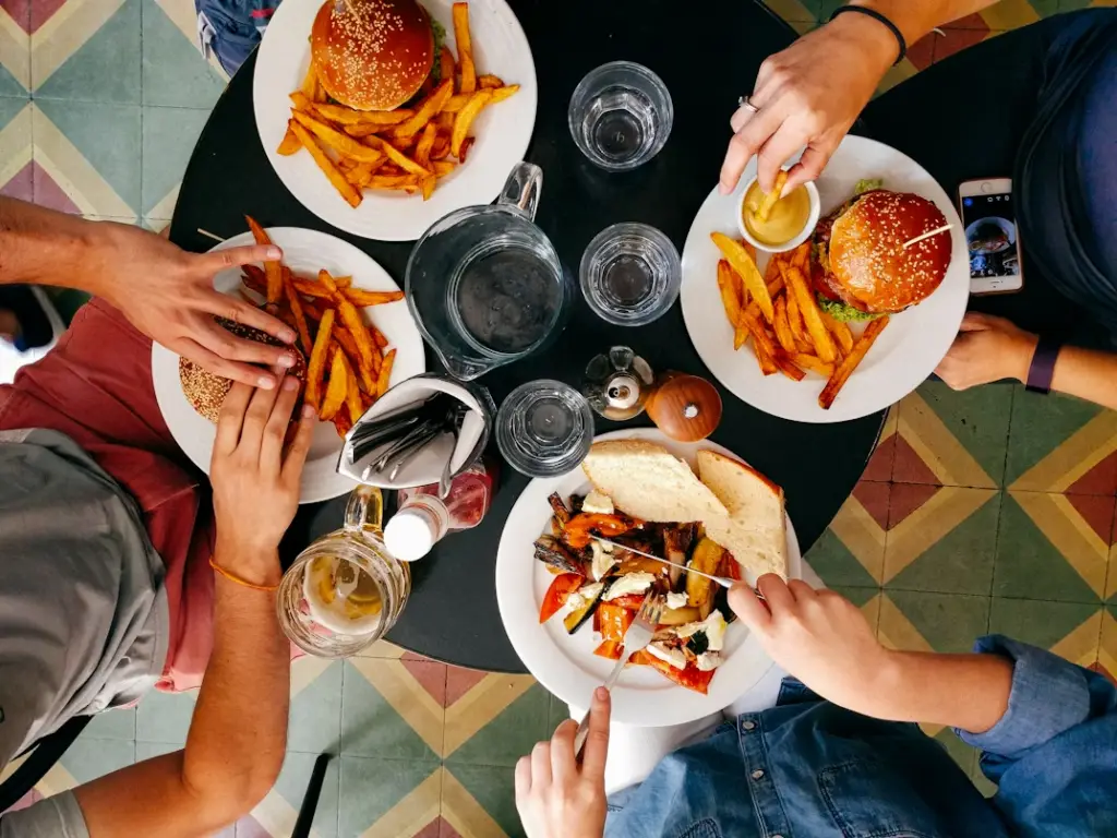 Friends sharing burgers, fries, and drinks around a table together