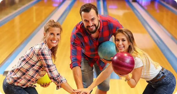 Couple and friend bowling together with help from an event host
