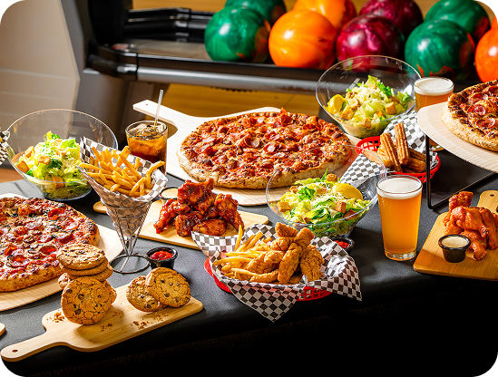 Table filled with pizza, wings, fries, and drinks for a group event