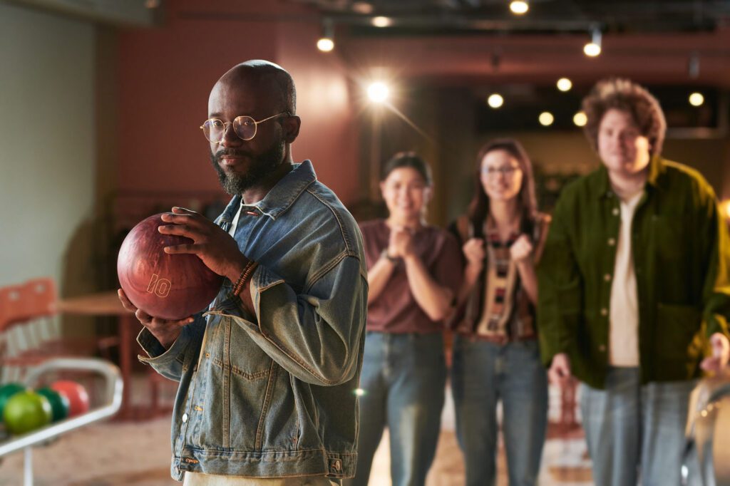 Man holding bowling ball while friends cheer at Cactus Bowl Tucson