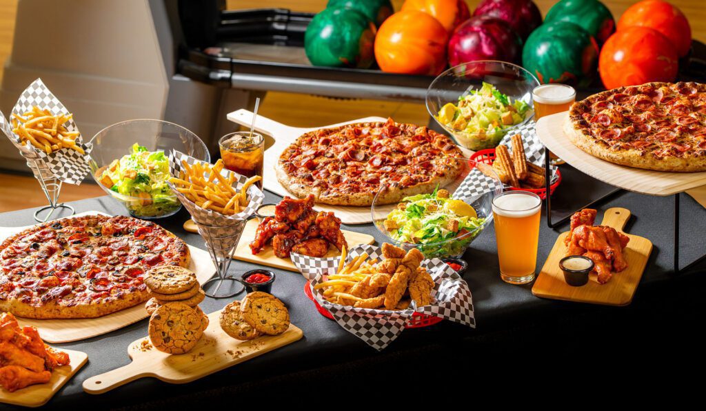 Large spread of pizza, fries, salad, and drinks for corporate catering