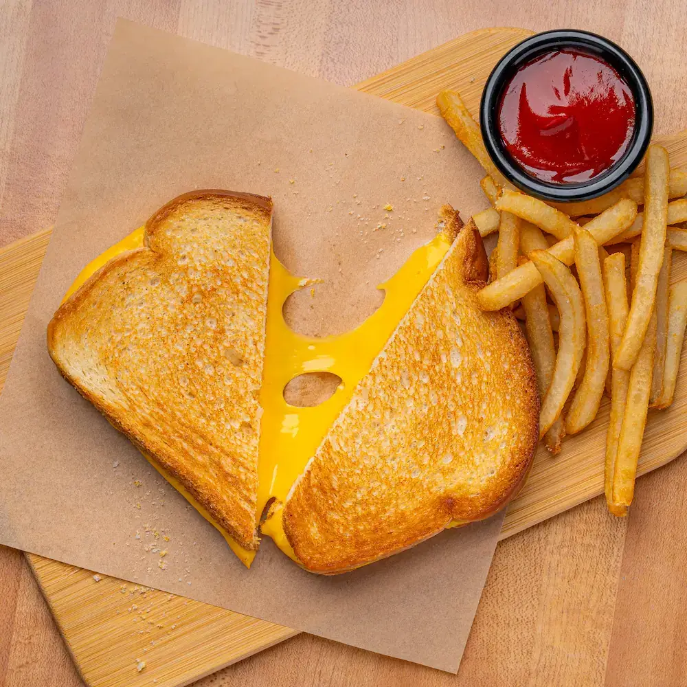 Toasted grilled cheese sandwich cut in half with melted american cheese served with crispy fries and a dipping sauce