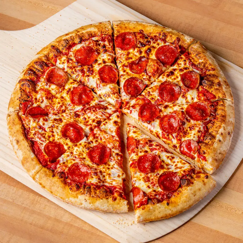 Whole pepperoni pizza with golden melted cheese on a wooden board