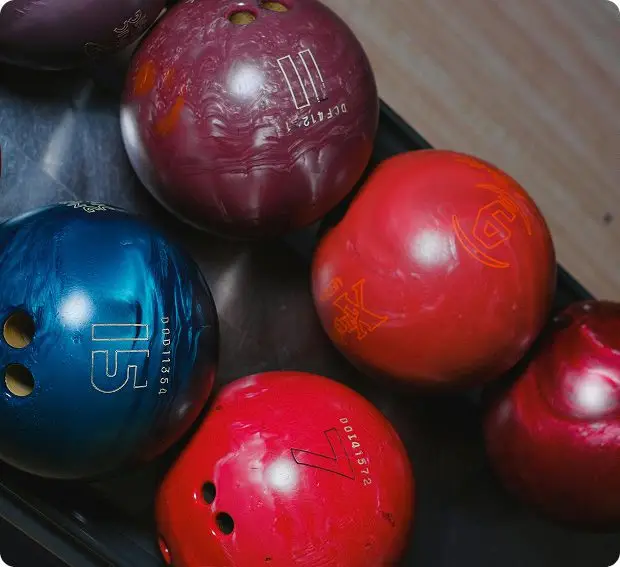 Close-up of colorful bowling balls in blue, red, and maroon on a rack